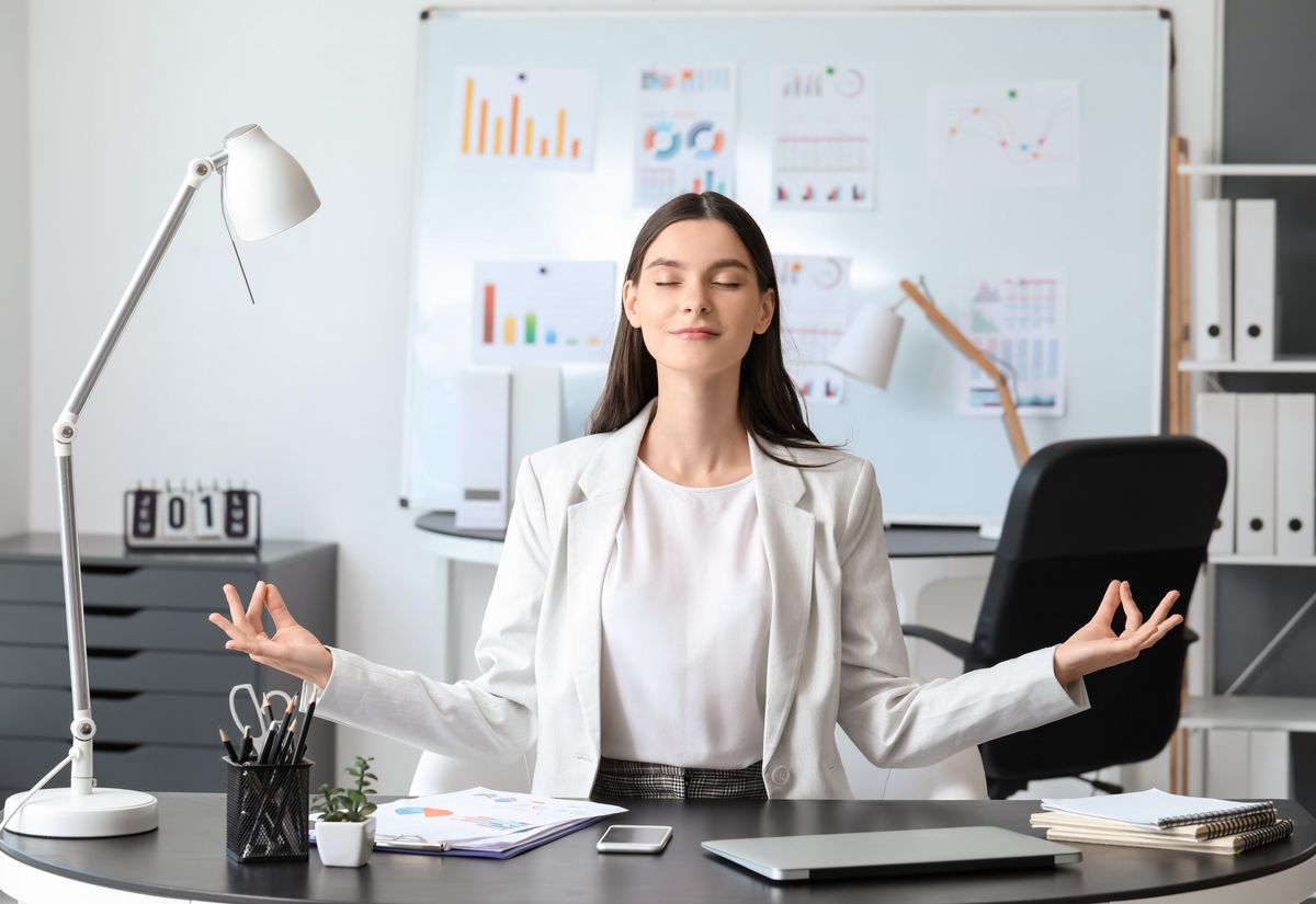 Office worker performing a seated overhead stretch at a modern desk